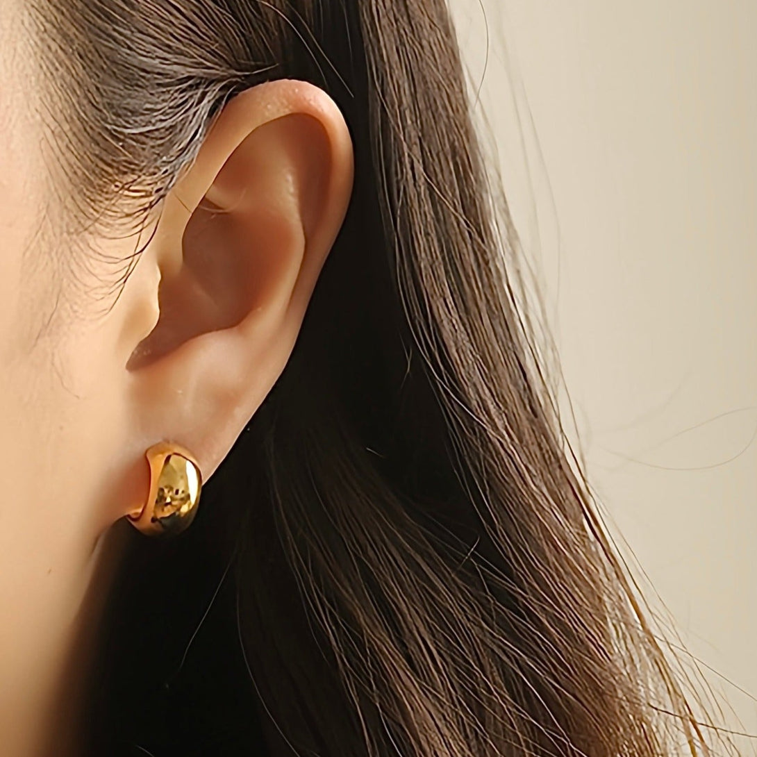 Eye-catching hoop earrings in warm 14K gold. The large, curved hoops have a tapered, wider base. Polished to a gleaming finish, the earrings fasten with friction clasps for a secure fit.  Materials: Eco Brass 18K Gold / White Gold Plating